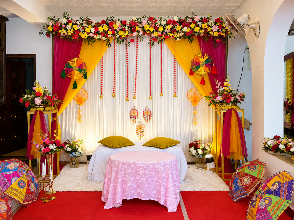 Haldi setup in pink and yellow drapes with paper fans, hanging tassels and painted parasols