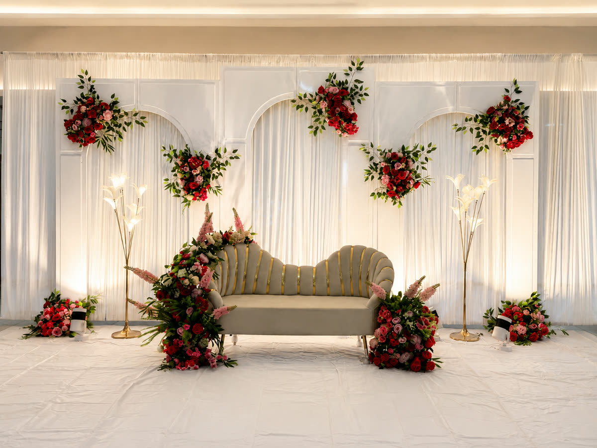 Reception backdrop of white drapes and deep red roses lit warmly from behind